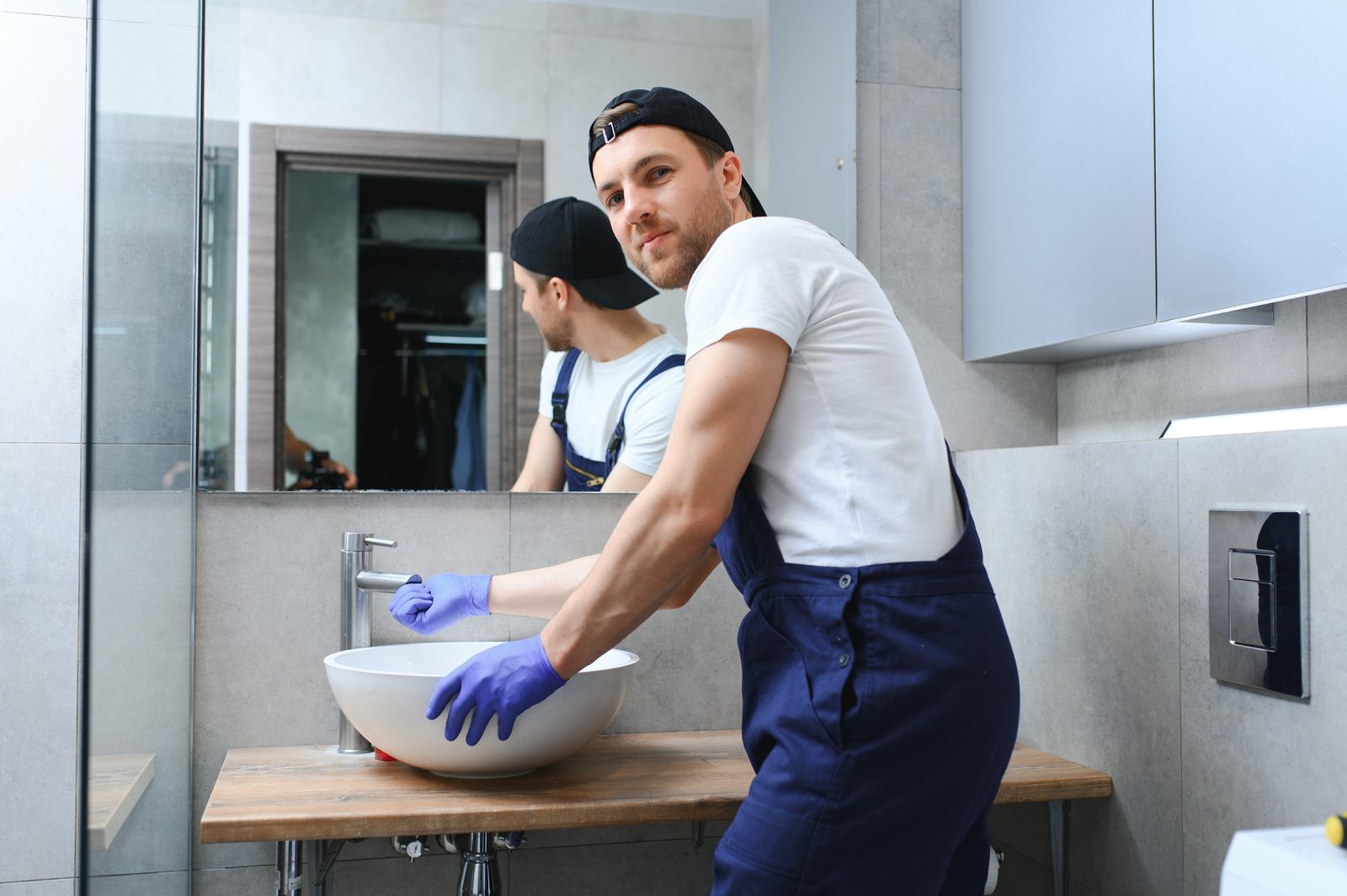 Plumber inspecting plumbing under a kitchen sink